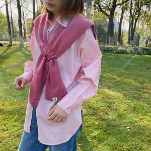 Knitted cross scarf shawl detail view, showing the soft pink texture and cozy styling.