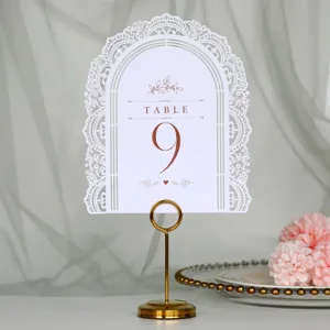 Vista dettagliata di un segnaposto da matrimonio bianco intagliato con supporto dorato e numero nove.