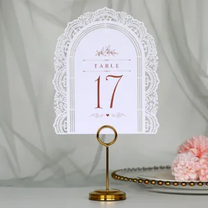 Primo piano di cartello numero tavolo matrimonio bianco tagliato al laser con supporto dorato.