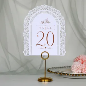 Primo piano di un numero da tavolo ad arco intagliato bianco con supporto dorato per matrimoni.
