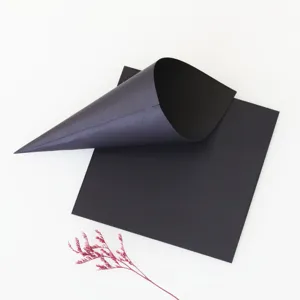 Vista de detalle de conos de confeti de papel negro y hojas sobre fondo blanco para bodas.