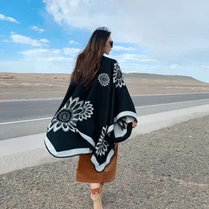 Detailed outdoor view of black knitted poncho with floral pattern, perfect travel style.