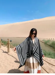 Vista detallada de la capa de punto negra y gris de mujer con motivo étnico para viaje.