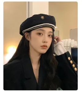 Dettaglio berretto con perle e strass, classico cappello nero in lana con elegante logo M.