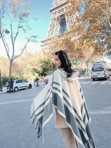 Detail view of the stylish hooded striped cape with fringe, outdoor fashion scene.