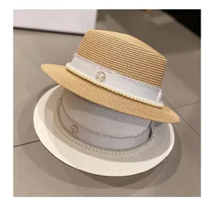 Detailed shot of elegant summer straw hats with pearl ribbon and metal decor, chic beach style.