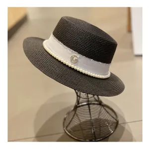 Detailed view of the black pearl straw hat with white ribbon, elegant summer beach sun hat.