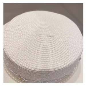 Close-up detail shot of the woven texture and decorative trim on a chic white summer straw hat.