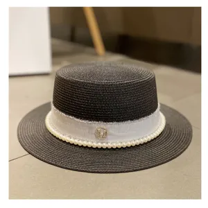 Elegant black straw boater hat with white ribbon and pearl trim for women summer beach vacation.