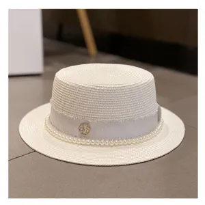 Detailed shot of elegant white straw hat with pearl trim and ribbon for summer beach wear.