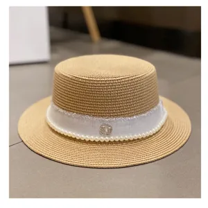 Detail view of the elegant straw hat featuring white ribbon, pearls, and sparkling metal badge.