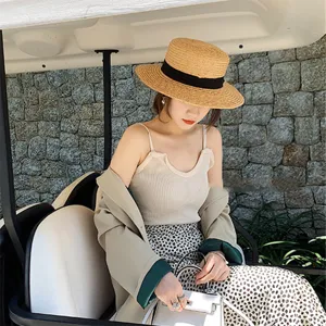 Detailansicht des Sommerstrohhuts im Golfcart, naturfarbenes Flechtmaterial mit schwarzem Band.