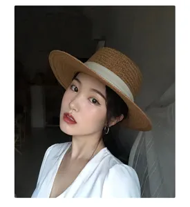 Gros plan détaillé du chapeau de paille plat vintage, avec tissage respirant et joli ruban.
