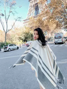 Detailed shot of women's hooded knit cape with chic stripes and stylish fringe accents.