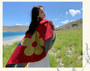 Detalle de capa tejida para mujer en viajes, rojo brillante con gran patrón de flores.