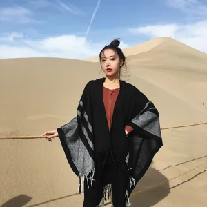 Detailed view of women's autumn winter hooded tassel poncho shawl in black and grey stripes.