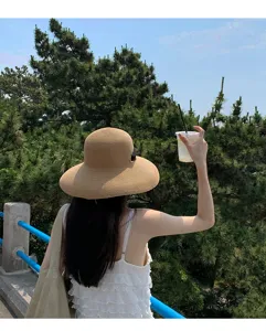 Vista dettagliata del cappello da sole in paglia a tesa larga con nastro nero all'aperto.