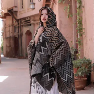 Detailed view of the ethnic style knitted hooded cape with zigzag pattern and fringe details.
