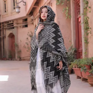 Detailed view of knitted hooded tassel shawl in classic chevron pattern for outdoor wear.
