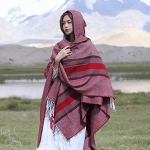 Detailed view of the autumn winter knit hooded poncho shawl with tassels in ethnic red stripes.
