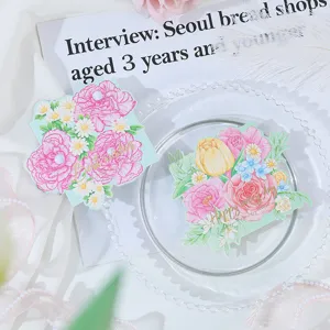 Detailed view of gold-stamped floral greeting cards with pearl decorations on a glass plate.