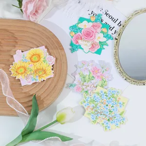 Detailed view of floral greeting cards with gold foil text, beautifully styled on flat lay.