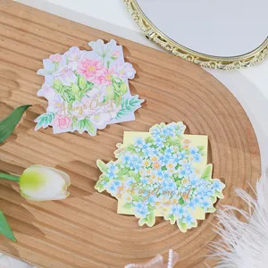 Close-up detail of shaped floral greeting cards with gold foil text on wooden tray backdrop.