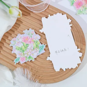 Detail view of die-cut floral greeting card with gold foil text on wooden tray with props.