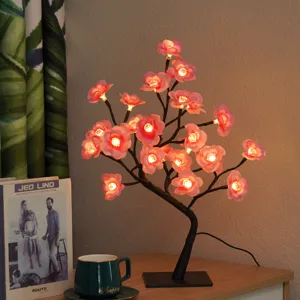 Detailopname van de LED bloesem boomlamp met warm gloeiende roze bloemen en zwarte takken.