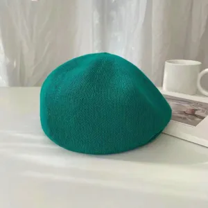 Detailansicht der grünen Strickberete, feine atmungsaktive Textur im schlichten ästhetischen Stil.