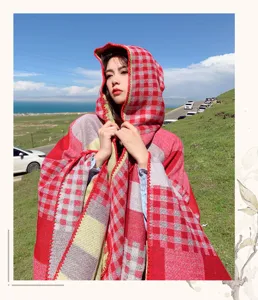 Close-up detail of red plaid hooded cloak shawl outdoor scenic wearing style appearance.