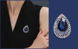 Detailopname van vintage druppel kristal broche met donkerblauwe steen en schitterende strass.