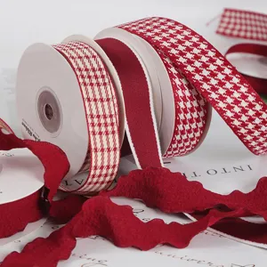 Close-up detail of wine red plaid and solid decorative ribbons for DIY gift wrapping.