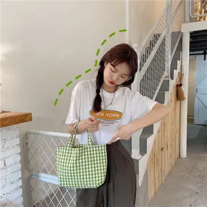 Small green checkered cotton lunch tote bag shown in a casual lifestyle setting