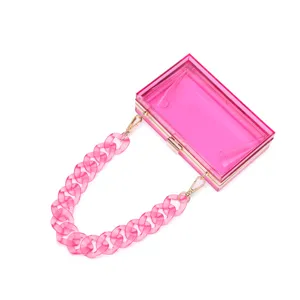 Transparent hot pink acrylic box clutch with chunky resin chain and gold frame.