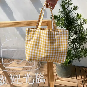 Close-up detail of a yellow and white gingham portable tote bag with wooden background