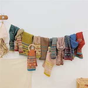Dettaglio sciarpa in maglia per bambini, scaldacollo in lana con motivo geometrico colorato autunno.