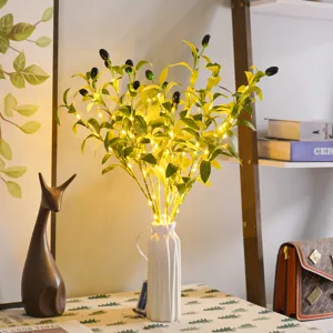 Detailed view of artificial olive branch with fairy lights in white ceramic vase for home decor