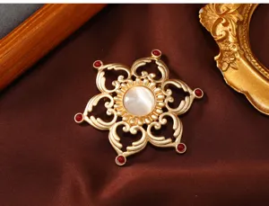 Detailed shot of retro gold hollow flower brooch with central white stone and red gem accents.