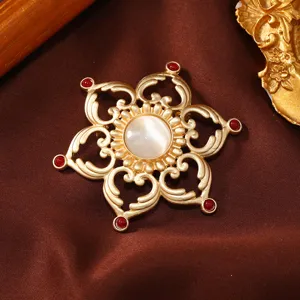 Vintage matte gold metal brooch with central white cat eye stone and red gems for women styling.