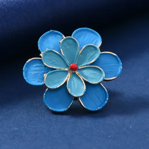 Close-up view of the vintage blue layered flower brooch, featuring fine petal texture and red bead.