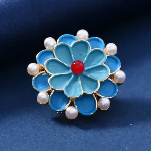 Close-up detail shot of the vintage enamel flower brooch with pearls and red center bead.