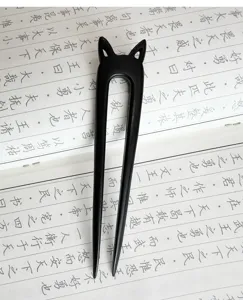 Vue rapprochée de l'épingle à cheveux minimaliste en bois noir en U avec design d'oreilles de chat.