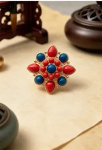 Vista dettagliata della spilla di loto stile etnico con pietre rosse e blu, rétro.