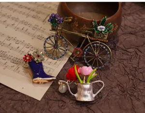 Detailaufnahme der Vintage Emaille Brosche mit Blumen und Fahrrad Motiven fuer Damen.