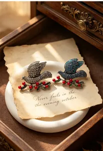 Detail shot of retro rhinestone peace dove brooches with red berries on a vintage white plate.