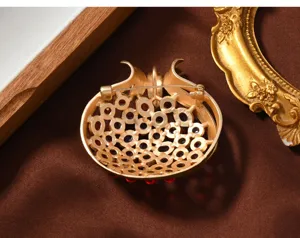 Close-up of retro matte gold pomegranate brooch back design, fine metalwork and red stone details.
