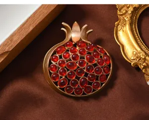 Vintage gold pomegranate brooch detail, exquisite red gemstone inlay, elegant suit accessory.