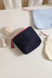 Detailed view of corduroy cosmetic bag featuring zipper closure and textured fabric in multiple soft colors.