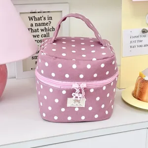 Detailweergave van schattige roze stippen cosmetische tas met handvat en handige rits.